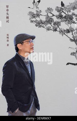 Wu Ming Yi poses in a studio setting, dressed in a black blazer and gray cap. He is a multidisciplinary Taiwanese writer and scholar Stock Photo