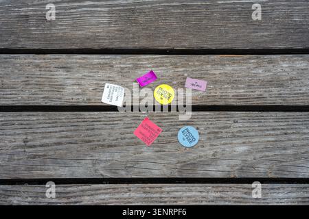 Lausanne, Switzerland - June 4, 2026: Small colorful paper labels scattered on weathered wooden planks, creating a rustic background with copy space. Stock Photo