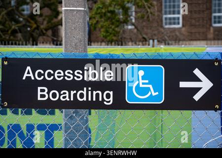 Accessible boarding sign with wheelchair symbol and directional arrow. Stock Photo