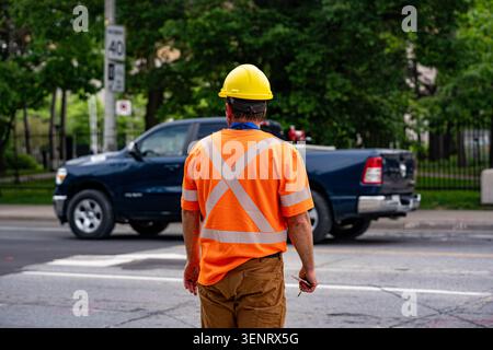 Construction worker wearing safety vest and hard hat near roadway. Stock Photo