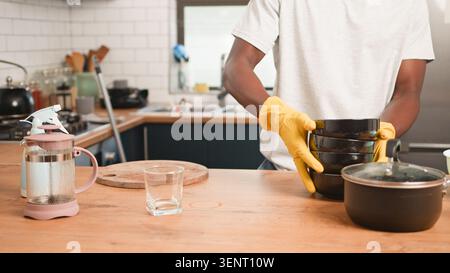Man Washing Dishes In Modern Kitchen Wearing Yellow Gloves While Stacking Bowls On Counter Stock Photo