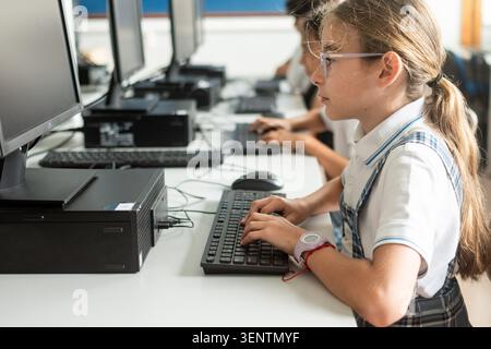 Focused primary school student typing on a desktop computer during an information technology class. Digital literacy, computer education, technology s Stock Photo