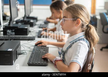 Focused primary school student typing on a desktop computer during an information technology class. Digital literacy, computer education, technology s Stock Photo