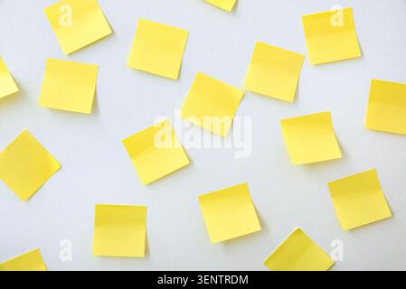 Multiple yellow sticky notes randomly arranged on a white background. Creative planning, brainstorming and organization concept with ample copy space. Stock Photo