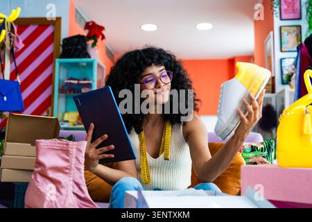 Beautiful young hispanic woman    managing her home clothing e-commerce business from home - Female entrepreneur owns online shopping store, concepts Stock Photo