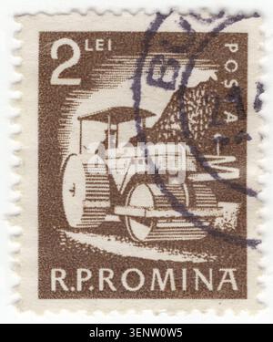 ROMANIA - 1960 June 11: 2 lei dark olive-gray postage stamp depicting road construction and infrastructure modernization in the post-war period, celebrating national development projects. The scene shows a heavy three-wheeled Steam road Roller leveling and compacting a new road surface. The silhouette of the driver is visible under the machine's protective canopy. In the background, a steep, rocky mountainside indicates the complex, rugged terrain being transformed by engineering projects and expansion of the national transportation network across the Romanian People's Republic Stock Photo