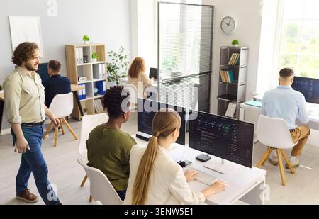 Programmers collaborating in open office workspace, coding software on computers Stock Photo