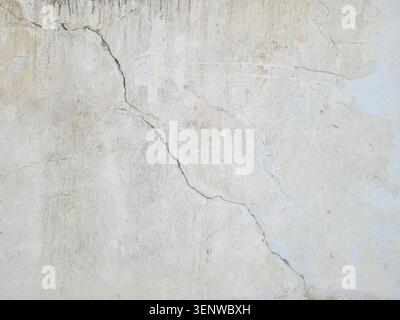 Long winding diagonal crack in the plastered surface of the wall of an old building.. Destruction caused by an earthquake. Cracked cement  wall Stock Photo