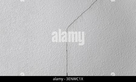 Large uneven crack in the concrete wall with abstract patterns. Problem in the walls of many buildings after an earthquake. Cracked cement  wall Stock Photo