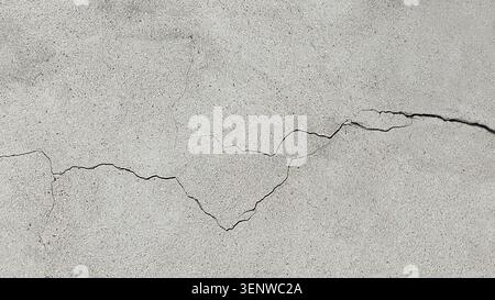 Long winding crack in the wall. Cracked concrete surface covered with gray cement mortar. Destruction after the earthquake. Copy space.  Repair Stock Photo