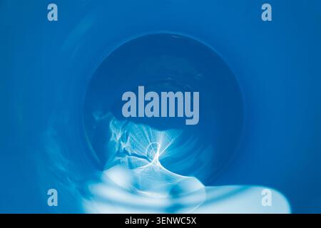 Optical refraction of light from the sun's rays on the surface of blue paint. Blurred image of a circular spot on the left with a gradient. Stock Photo