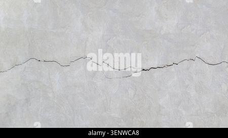 Cracked concrete surface covered with gray cement mortar. Destruction after the earthquake.  Thin long winding cracks in the wall. Copy space. Texture Stock Photo