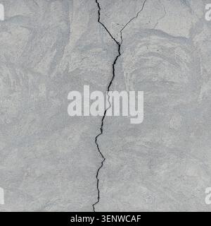 Cracked concrete surface covered with gray cement mortar. Destruction after the earthquake. Rough winding cracks on the wall. Copy space. Texture Stock Photo