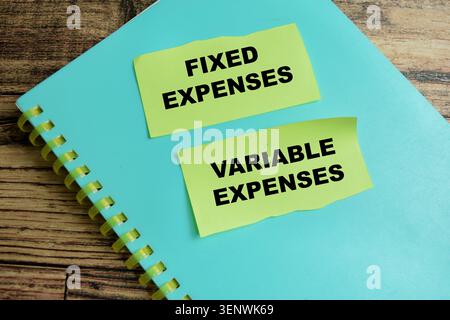 Concept of fixed expenses and variable expenses write on sticky notes isolated on Wooden Table. For allow you to map out exactly where your money goes Stock Photo
