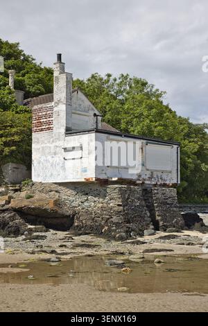 The historic white bathing house built on a stone foundation at the edge of the beach, Penrhos Coastal Park, Isle of Anglesey, North Wales. Stock Photo
