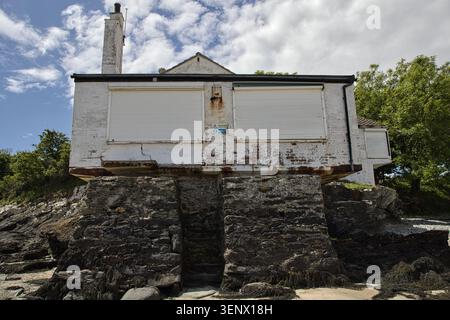 Low-angle view of the historic white bathing house on its dark stone base against a cloudy sky, Penrhos Coastal Park, Anglesey, Wales. Stock Photo