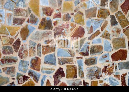 Background created with the exterior wall of a house made of natural stones of multiple colors Stock Photo