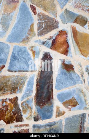 Background created with the exterior wall of a house made of natural stones of multiple colors Stock Photo