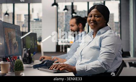 Portrait of black interior designer using high tech software for modern layout, 3D modeling program to design construction floor plan. Architectural blueprints on dual monitors, virtual assets. Stock Photo