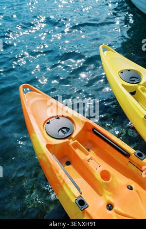 Brightly colored kayaks resting on clear water Stock Photo