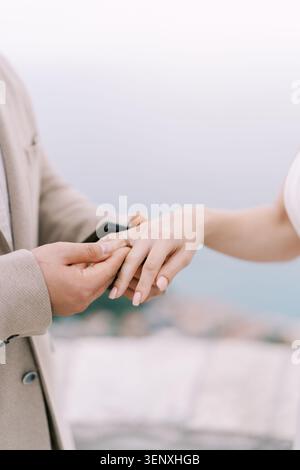 Man placing engagement ring on womans finger outdoors Stock Photo