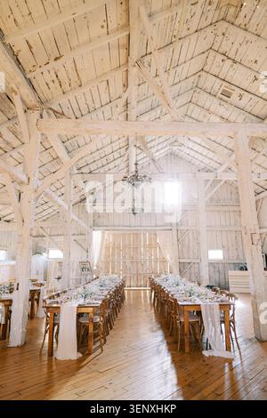 Rustic wedding dinner setup in white wooden barn Stock Photo
