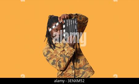 Male model posing with clapperboard in front of camera, using movie production instrument to cut scenes and say action, with film director and producer holding flap board. Stock Photo
