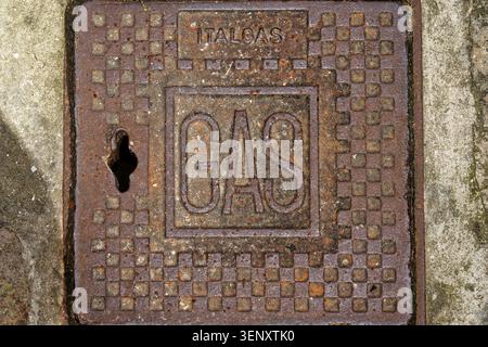 Close-up of a weathered, square cast iron utility cover with "GAS" and "ITALGAS" lettering embossed on a stone pavement in Italy Stock Photo