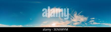 Sky clouds panorama shows soft white cirrus clouds scattered across a vast blue horizon at sunset with copy space Stock Photo