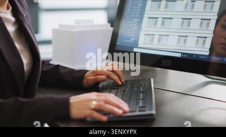 Skilled designer using 3D modeling tools to develop designs for buildings, create architectural plans at desk, woman performing engineering task with CAD software app in a startup office. Stock Photo