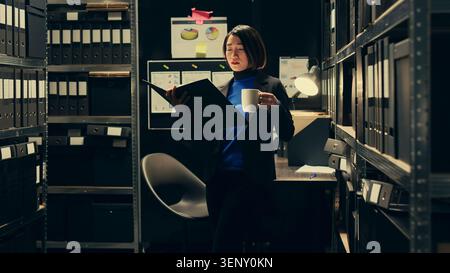 Portrait of investigator tracking financial transactions registered in the archives folders, looking for similarities and clues on criminology documents, law agent working on forensics. Stock Photo