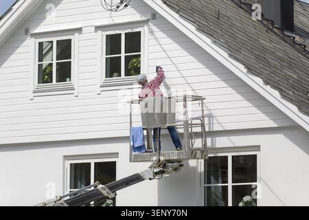 Man on a lift painting his house Stock Photo