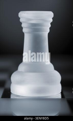 Glass chess rook is standing on board in dark Stock Photo