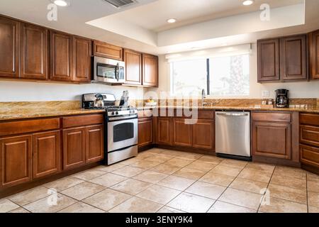 Large open kitchen with warm wood cabinets paired with light granite countertops and stainless steel appliances Stock Photo