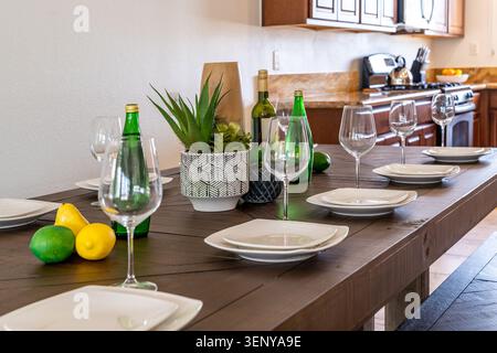 Plates and wine glasses set for dinner or lunch on a modern rustic wooden dining table Stock Photo