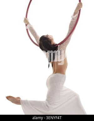 Rear view of aerial acrobat doing acrobatic tricks with ring. Young flexible aerialist performing with hoop on white isolated studio background Stock Photo