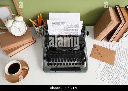 Vintage typewriter with blank paper, books, alarm clock, and coffee cup on white desk for creative writing Stock Photo