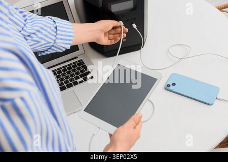 Person connecting USB cable to portable power station for charging laptop, tablet, and smartphone devices Stock Photo