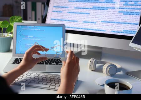Female programmers hands with eyeglasses at table in office, closeup Stock Photo