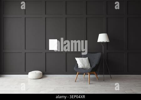 Modern minimalist living room interior with dark gray wall paneling, armchair, floor lamp, and light wood flooring Stock Photo