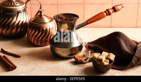 Traditional turkish coffee pot with freshly brewed coffee, cinnamon sticks, and brown sugar cubes Stock Photo