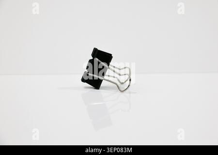 Black Metal Binder Clips on White Background, Close-Up of Office Stationery Supplies, Minimalism Concept for Business and Education Desk Equipment Stock Photo