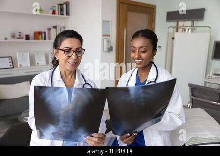 Two positive multiethnic female doctors reviewing spinal X-ray images Stock Photo