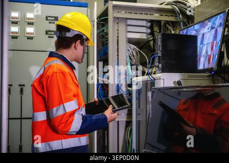 IT technician holding tablet inspecting server rack network data center, maintaining telecommunication server room, checking cables mainframe cabinet, Stock Photo