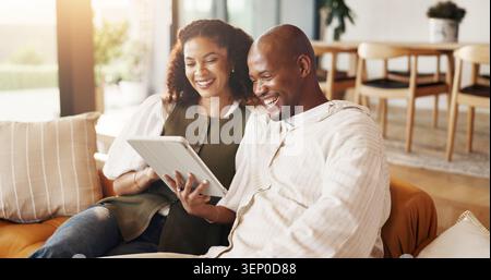 Couple, relax and watching video on sofa with tablet, bonding together and laugh for comedy movie. Married, African people and tech in home with Stock Photo