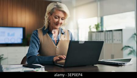 Business, woman or typing on laptop in office for data extraction, investment memo draft or email. Financial analyst, mature person or tech for budget Stock Photo