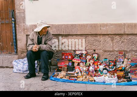 Cusco, Peru - March 23, 2025: An elderly Peruvian man selling handmade crafts souvenirs outside the San Pedro Market Stock Photo