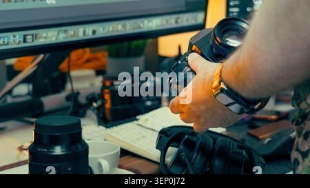 Photographer hand holding retro film camera workspace studio table desk. A close up shot of a creative professional content creator checking an analog Stock Photo