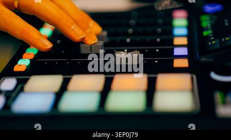 Sound designer fingers moving sliders audio mixing console backlit pads close up. A production specialist adjusts volume levels and controls tracking Stock Photo