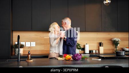 Dancing, happy and senior couple in kitchen for cooking with bonding, connection or marriage in house. Smile, ingredients and elderly man with woman Stock Photo